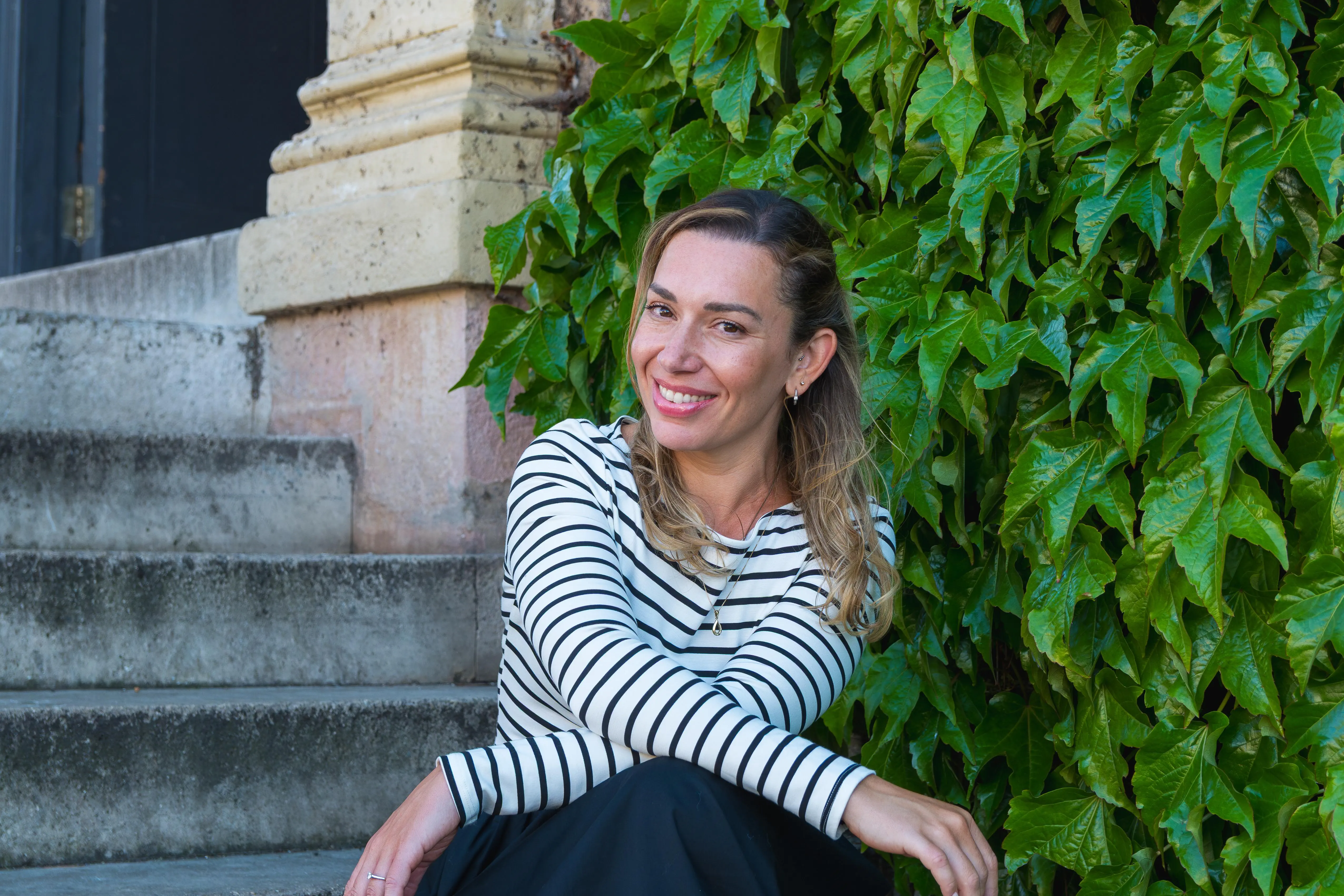 A female business woman smiles to the camera posing on some stone steps